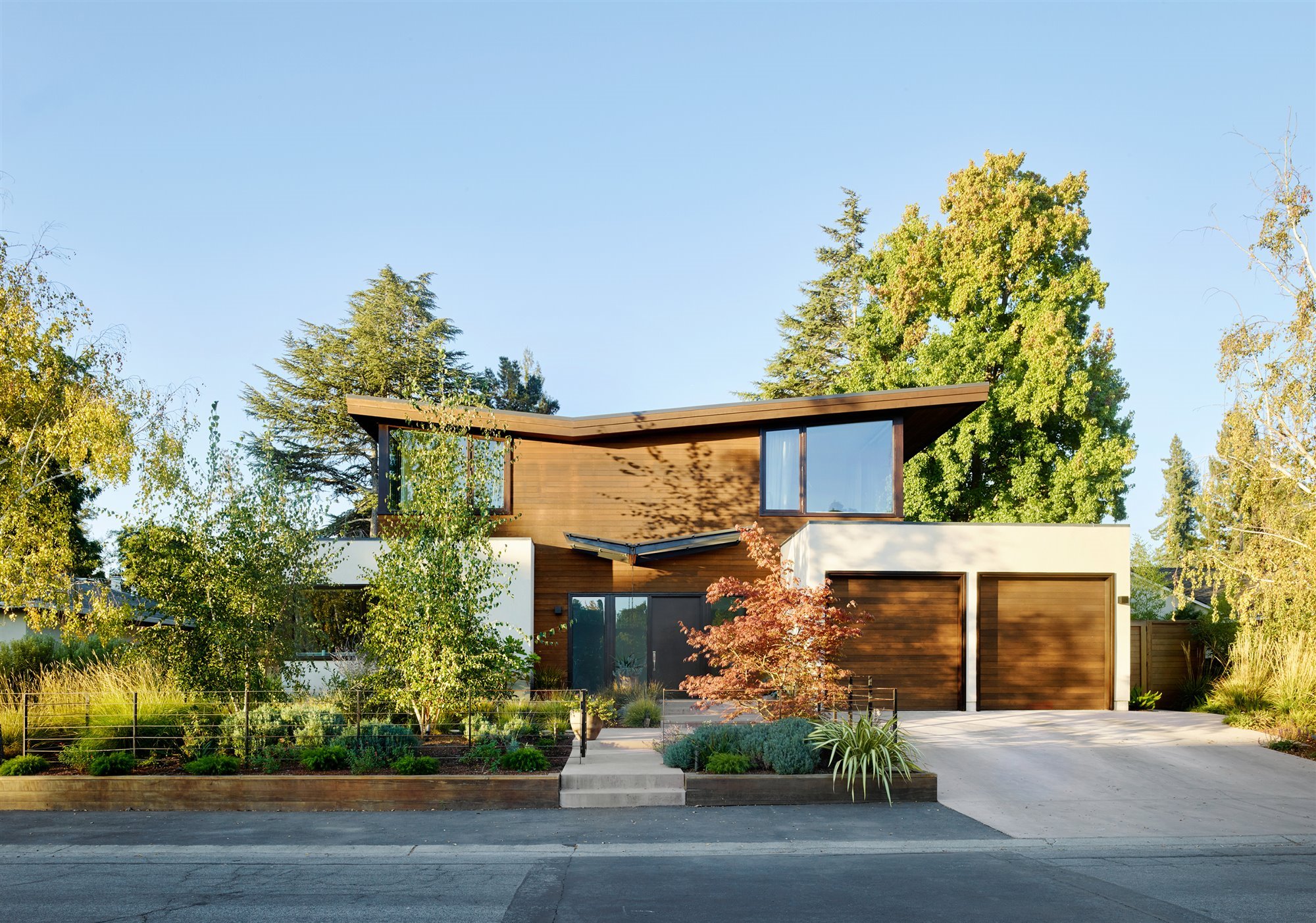 Una casa moderna con dos fachadas una de cristal y otra de madera
